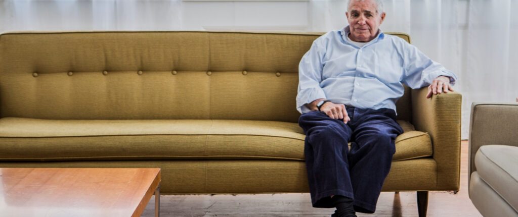 Ein älterer Mann sitzt allein auf einem Sofa