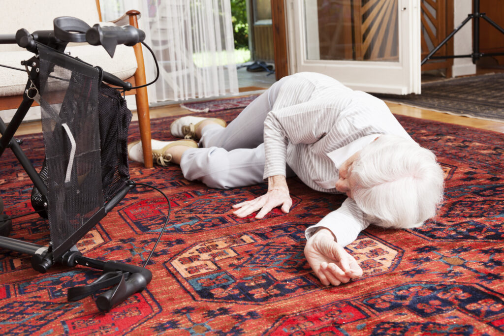 Eine alte Frau liegt neben ihrem umgestürzten Rollator auf dem Fußboden
