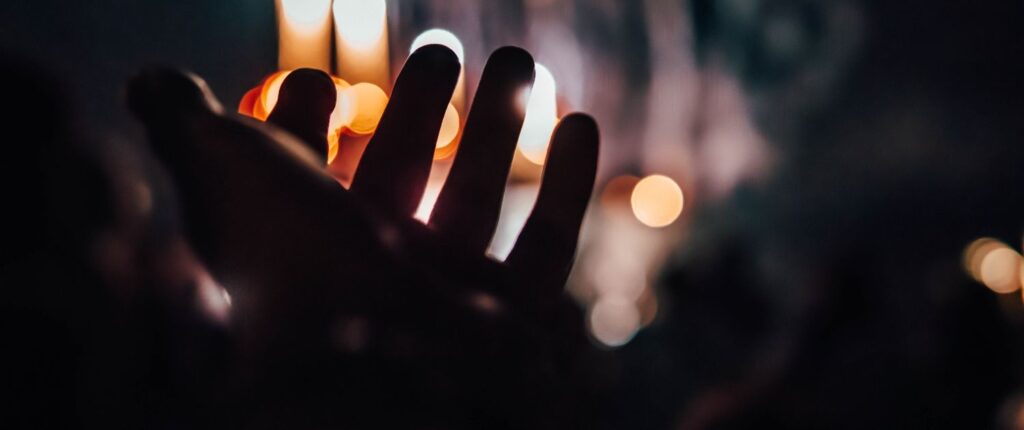 Eine Hand im Gegenlicht vor Kerzenschein