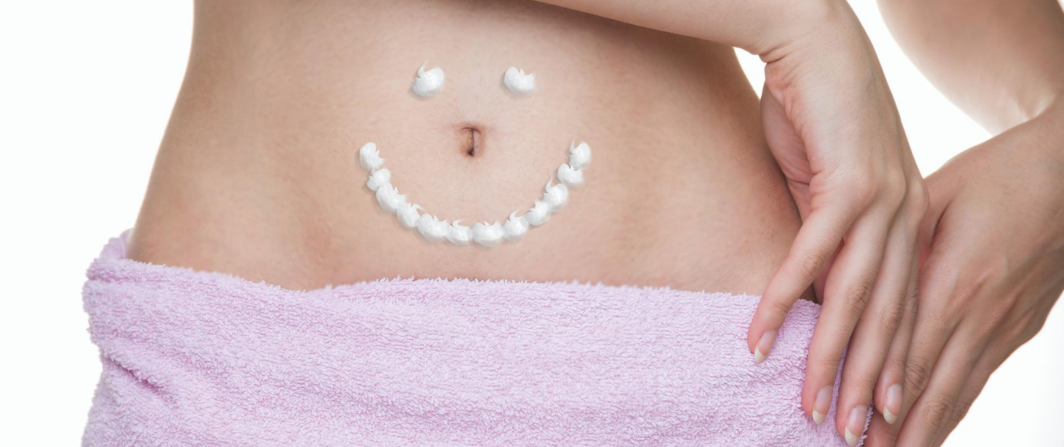 Glücklicher Bauch ohne Verstopfung. Ein aus Body Lotion gemalter Smiley auf einem Bauch.