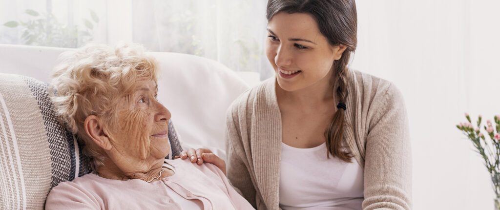 Eine alte Frau in einem Krankenhausbett wird von ihrer Tochter besucht.