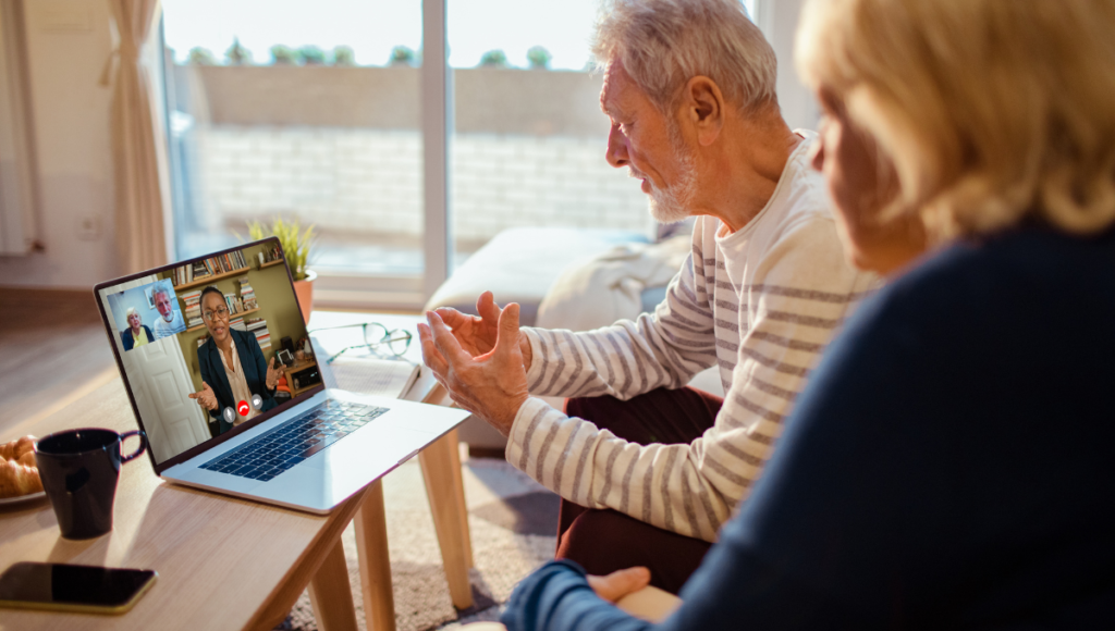 Ein Mann und eine Frau sitzen gemeinsam vor einem Laptop und führen ein Gespräch per Video.