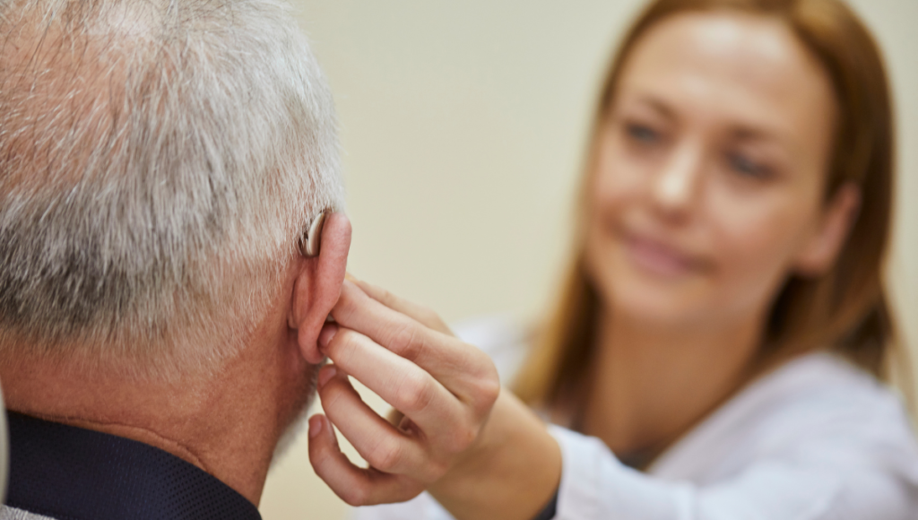 Schwerhörig: Eine Ärztin passt das Hörgerät eines Patienten an.