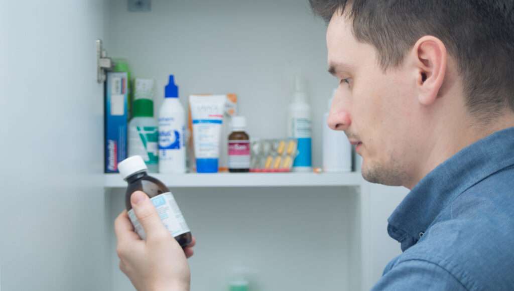 Medikamente im Medikamentenschrank werden von einem Mann überprüft.