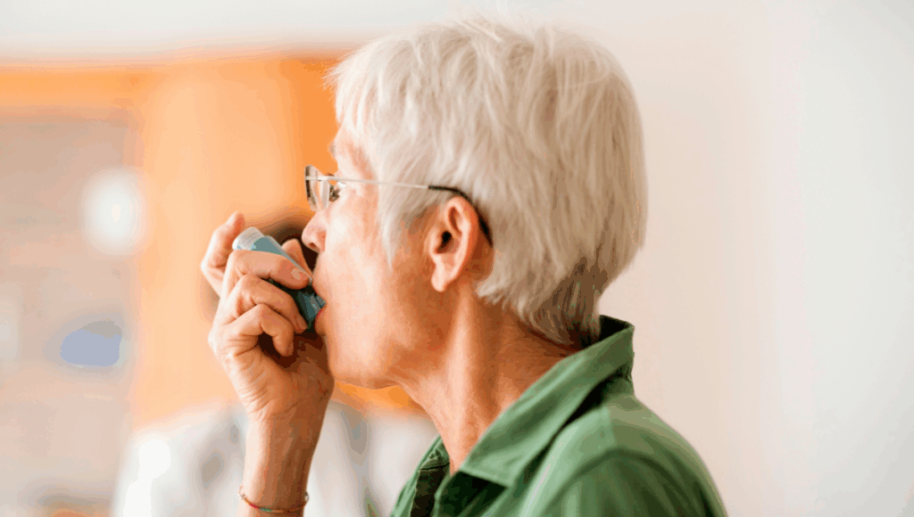 Eine Frau hält ein Asthmaspray in der Hand und nimmt einen Hub.